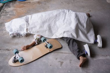 Ölü adam beyaz bir torbaya ya da kazadan ya da kurbanın evinde öldürülmekten dolayı örtülmüş bir cesede uzandı. Covid-19 hastalığı düşük sağlık hizmetlerinden bir insanı alıp götürdü. Sörf tahtası kazası.