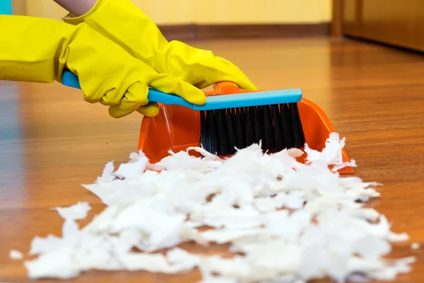 Chica barriendo el suelo con un cepillo en la pala . — Foto de Stock