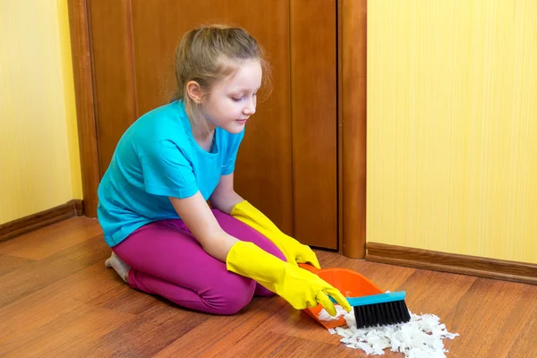 Menina varrendo o chão com um pincel na colher . — Fotografia de Stock