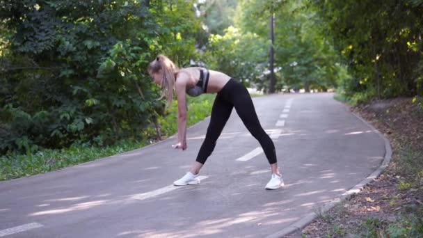 Перед бегом спортсменка растягивает ноги для разминки — стоковое видео