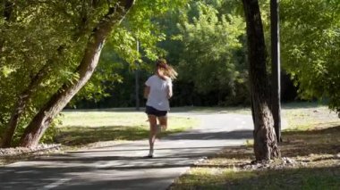 Yaz parkında asfalt yolda koşan kadın. 