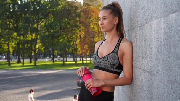 Mujer cansada beber agua botella roja después del entrenamiento de la mañana — Vídeo de stock