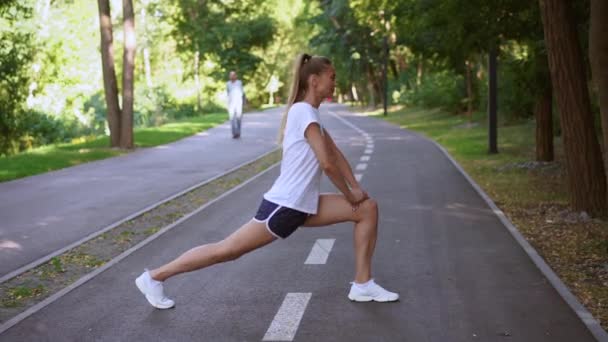 Žena běžec protáhnout nohy před cvičením v letním parku ráno — Stock video