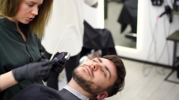 Joven hermosa mujer caucásica peluquería corta barba hombre guapo en la barbería moderna — Vídeos de Stock