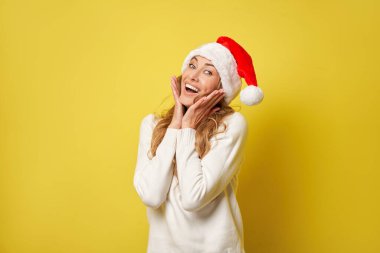 Noel Baba Kadın Noel Baba, beyaz kazak, sarı stüdyo arka plan güzel beyaz kadın kıvırcık saç portresi Mutlu insan, olumlu duygu, tatil kavramı.