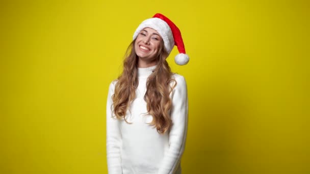 Vrouw kerstman hoed geel studio achtergrond mooie Kaukasische vrouw krullend haar portret — Stockvideo