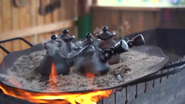 Coffee preparation. Traditional Turkish process making espresso coffee on hot sand in ceramic Cezve on fire outdoors — ストック動画