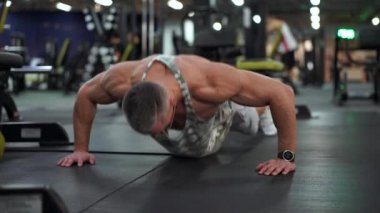 Kas atletik vücut geliştirme fitness modeli spor salonu zemininde şınav çekiyor. 