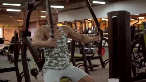 М'язистий спортивний культурист сидить на лавці тренування м'язів грудей на фітнес-обладнанні — стокове відео