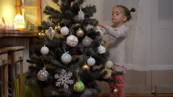 Menina feliz decorando árvore de Natal com bolas. Estilo de vida atmosfera acolhedora. Férias em casa conceito. — Vídeo de Stock