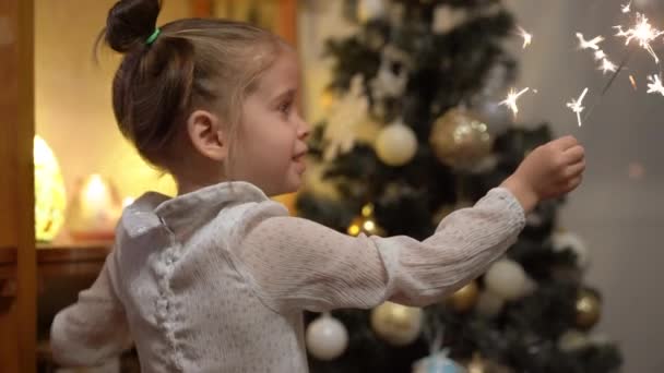 Glückliches kleines Mädchen schmückt Weihnachtsbaum mit Kugeln. Lifestyle gemütliche Atmosphäre. Urlaub zu Hause Konzept. — Stockvideo