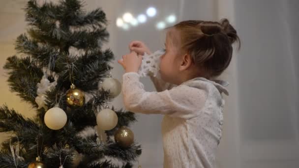 Joyeux petit fille décorant l'arbre de Noël avec des boules. Style de vie atmosphère chaleureuse. Vacances à la maison concept. — Video