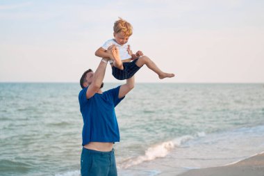 Baba oğul deniz tatilinde birlikte vakit geçiriyor. Küçük çocuk plajda yürüyor. Babalar günü. Tek çocuklu bir aile. Babanızla mutlu bir çocukluk. 