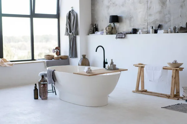 Birçok aksesuarlı, büyük pencerenin yanındaki modern beyaz banyo.