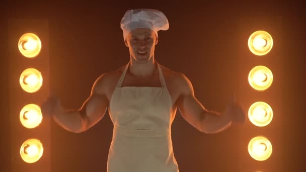 Portrét svalnatého kuchaře v bílé zástěře a kuchařské čepici na zakouřeném pozadí — Stock video