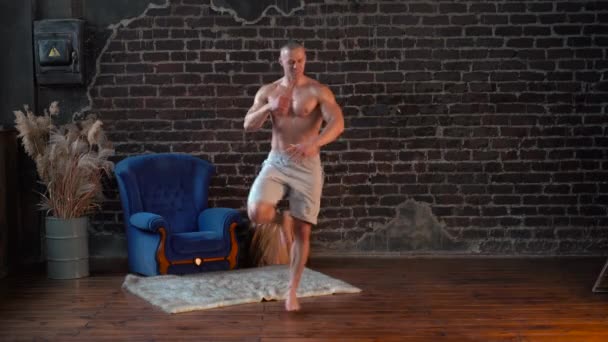 Široký záběr Mladý svalnatý muž bez košile tančící aktivní pohyby doma — Stock video