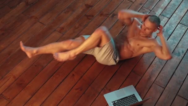 Uomo sportivo che fa addominali esercizi scricchiolii sul pavimento a casa, ampia vista dall'alto — Video Stock