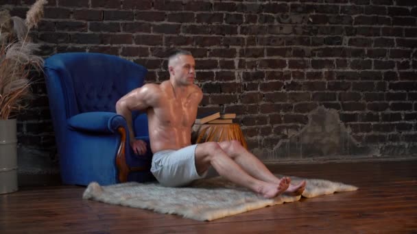Široký záběr boční pohled atletický chlap dělá push up cvičení doma na modrém křesle — Stock video
