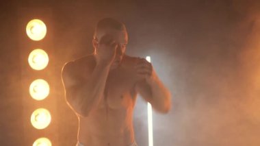 Kameraya yumruk atan erkek boksör ve dumanlı arka planda eldivensiz üstsüz atlet boksör. 