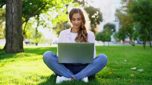 Mujer de negocios sentado césped parque de verano utilizando portátil persona de negocios trabajando a distancia. Al aire libre — Vídeo de stock