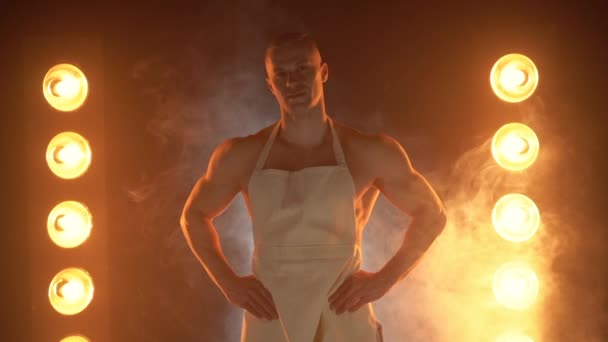 Retrato de chef musculoso con delantal blanco y sombrero de chef sobre fondo ahumado — Vídeo de stock