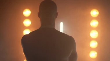 Beyaz önlük giymiş kaslı bir aşçının portresi ve dumanlı arka planda şef şapkası. 