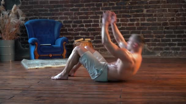 Sportovní muž dělá břišní cvičení křupky na podlaze doma, boční pohled. 