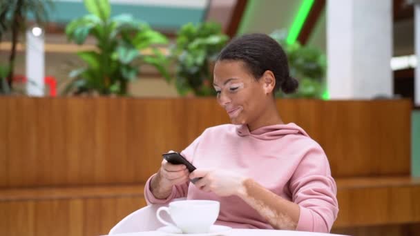 Чорно-африканська американська жінка з вітиліго проблема пігментації шкіри в приміщенні одягнена рожева капюшона — стокове відео