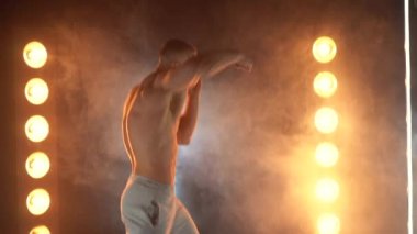 Kameraya yumruk atan erkek boksör ve dumanlı arka planda eldivensiz üstsüz atlet boksör. 