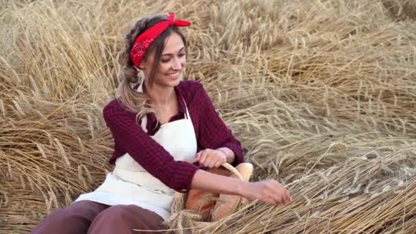 Buğday tarlasında oturan kadın çiftçi Hasır sepet ekmeği taşıyan fırıncı kadın — Stok video