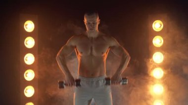 Koltuk değnekleriyle omuzlarını kaldıran genç, silah eğitimi alan, dumanlı, aydınlık bir arka plan.