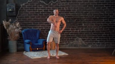 Geniş açı Genç kaslı üstsüz adam evde aktif dans ediyor