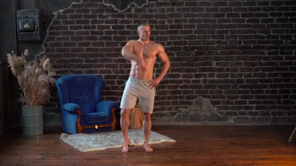 Wide shot Joven musculoso sin camisa hombre bailando movimientos activos en casa — Vídeo de stock