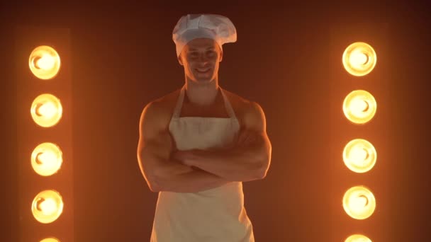 Portrét svalnatého kuchaře v bílé zástěře a kuchařské čepici na zakouřeném pozadí — Stock video