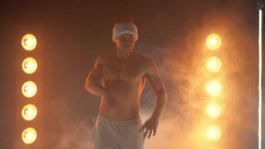 Noel dansları. Noel Baba şapkalı neşeli kaslı adam yanan lambaların üzerinde komik bir şekilde dans ediyor. 