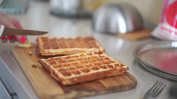 Mãos femininas corta um delicioso waffles belgas com uma faca na cozinha em casa Foco seletivo — Vídeo de Stock