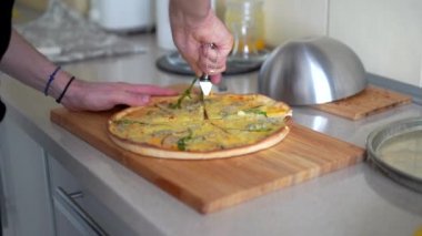 Pizza kesme makinesi ile pizza kesen bir adam. 
