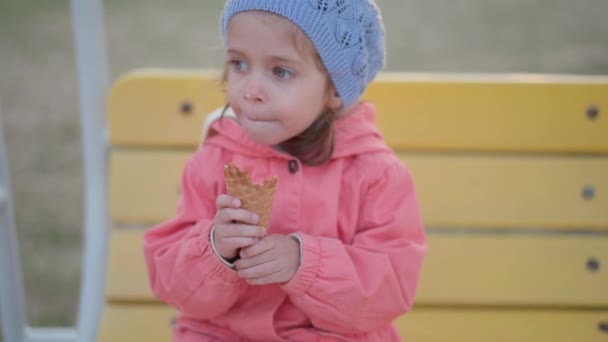 Klein meisje eet buiten ijs. blank vrouwelijk kind genieten terwijl likken wit ijs in wafel kegel — Stockvideo