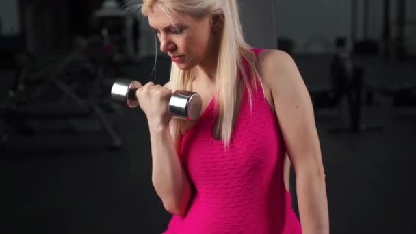 Pregnant woman lifting up dumbbells training biceps muscle at the gym sitting bench — Stock Video