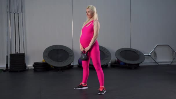 Mujer embarazada levantando pesas de pesas musculatura piernas de entrenamiento en el gimnasio — Vídeo de stock