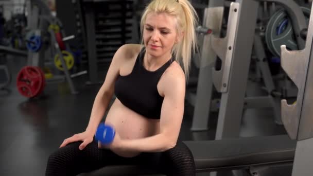 Έγκυος γυναίκα ανύψωση αλτήρες προπόνηση δικέφαλους μυς στο γυμναστήριο συνεδρίαση πάγκο — Αρχείο Βίντεο