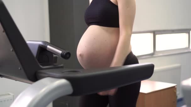 Machine de tapis roulant d'entraînement de femme enceinte dans la salle de gym Exercices cardio sur simulateur de course — Video