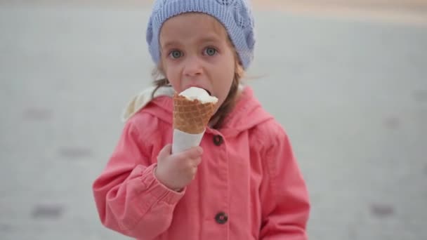 La bambina mangia gelato all'aperto. caucasico femmina bambino godere mentre leccare bianco gelato in cialda cono — Video Stock