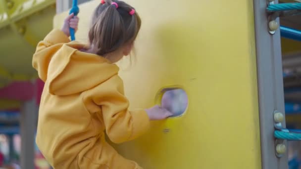 Niña. Niña jugando en el patio de recreo. Escalada marco de escalada — Vídeo de stock