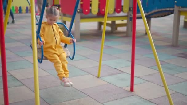 Bambina. Una ragazzina gioca al parco giochi. oscillare su un'altalena — Video Stock