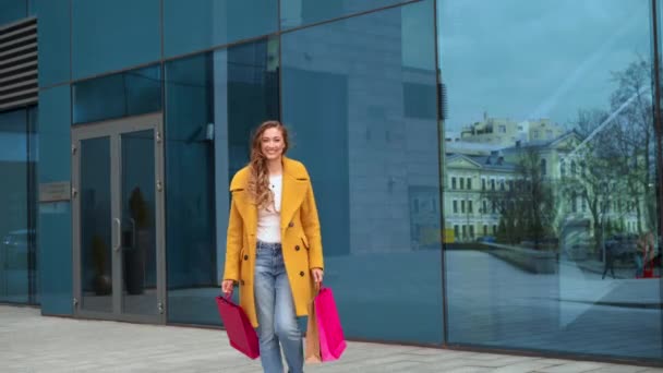 Biznes kobieta z torby na zakupy ubrany żółty płaszcz spacery na zewnątrz korporacyjny budynek tło Taniec Happy Funny — Wideo stockowe