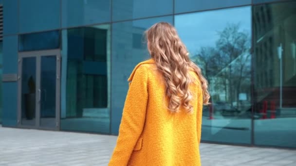 Επιχειρηματίας με τσάντες ψώνια ντυμένο κίτρινο παλτό περπάτημα σε εξωτερικούς χώρους εταιρικό κτίριο φόντο — Αρχείο Βίντεο