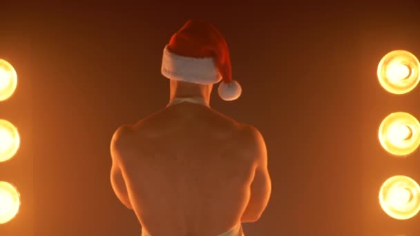 Förförisk muskulös kille i förkläde och Santa hatt framöver, vänder sig till kameran och lockar med fingret, slow motion — Stockvideo