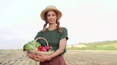 Kadın çiftçi hasır şapka önlüğü ayakta duran tarım arazisi gülümseyen tarımcı kadın tarım uzmanı mutlu Kafkas işçi tarlası