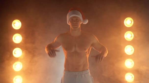 Retrato de muscular homem vestindo Natal Santa chapéu, mostrando polegar para cima no fumegante fundo — Vídeo de Stock